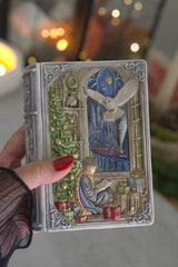 Hand holding the Enchanted Book Candle with detailed owl, train and winter fantasy cover