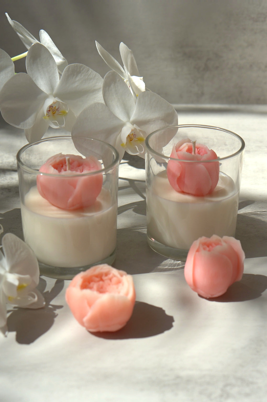 Peony Bloom soy candle displayed with pink wax peonies and white orchids