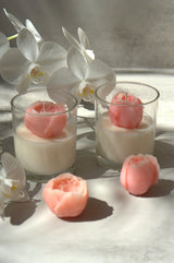 Peony Bloom soy candle displayed with pink wax peonies and white orchids